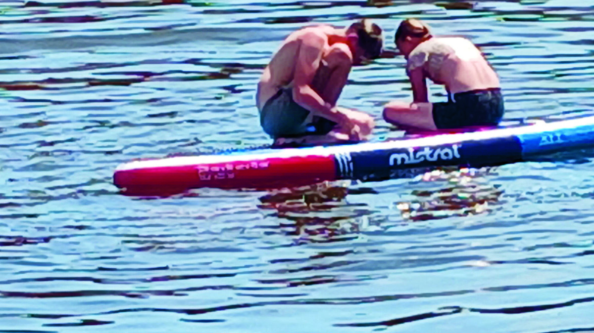 Zittend op een surfplank bij het Stadsstrandje